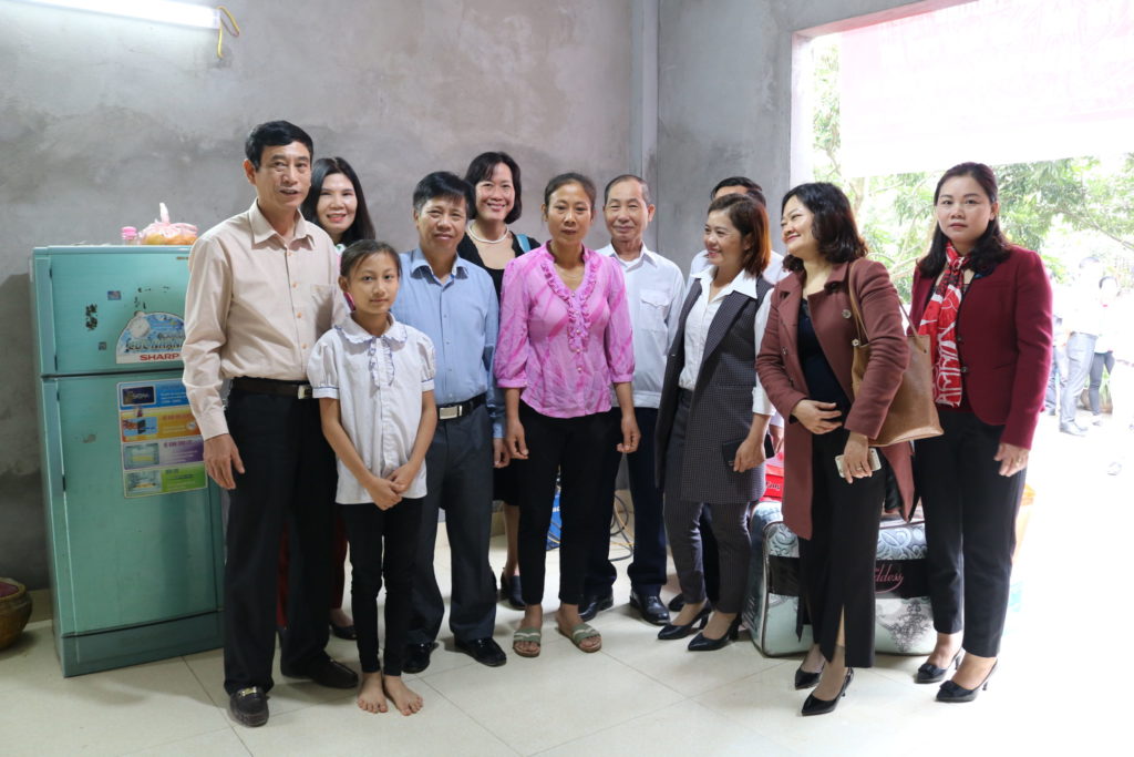 The Nguyen family inside their new home with government officials and Holt Vietnam staff.