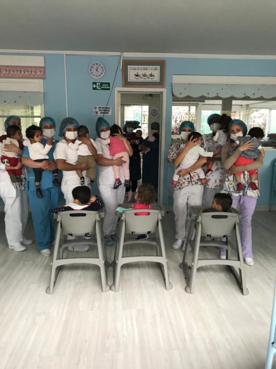 Caregivers wear masks provided by donors as they hold children at our partner care center in Bogotá. 
