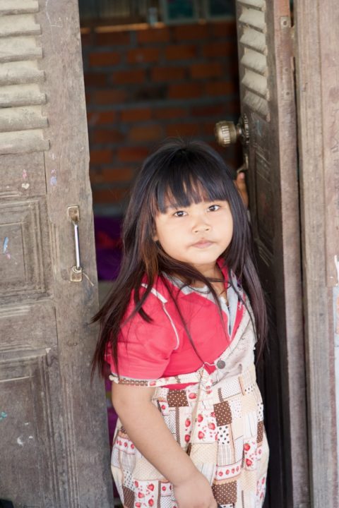 Ary's daughter stands in the doorway of their home in Battambang. 