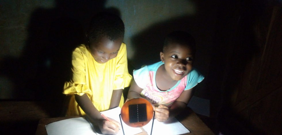 two little girls studying with a solar lamp in uganda