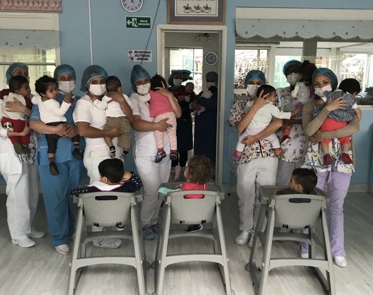 group of caregivers holding babies in masks