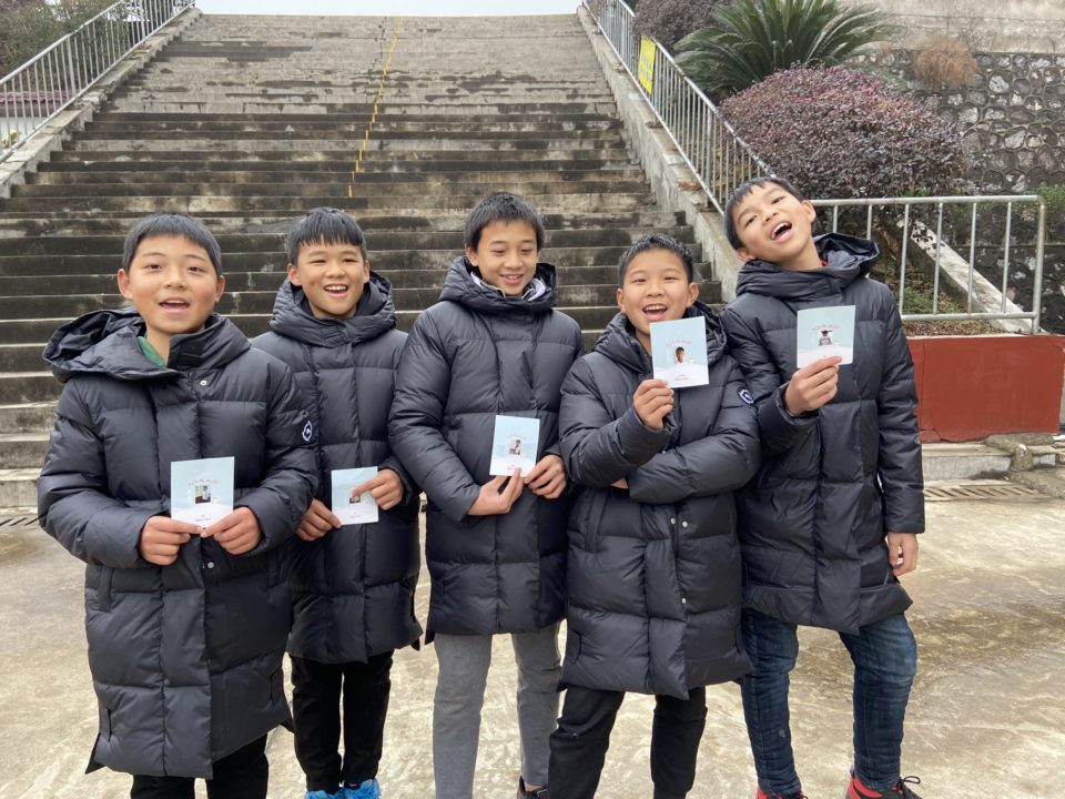 Wearing their new winter coats, children pose for a picture with the Christmas cards they received from their sponsors