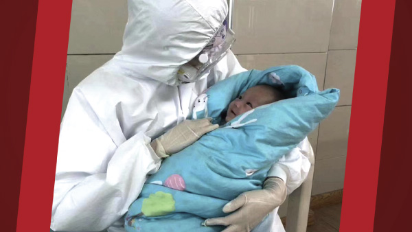 caregiver in PPE holding a baby