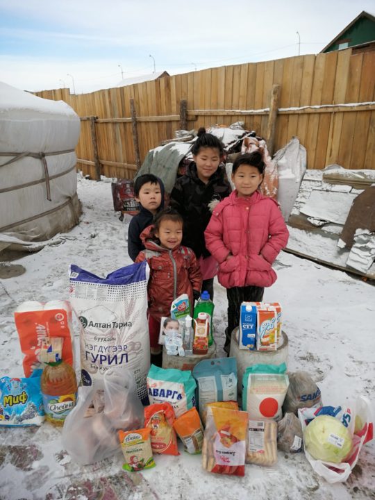 Children who live near the Red Stone School in Mongolia stand with an emergency food delivery they received during the pandemic.