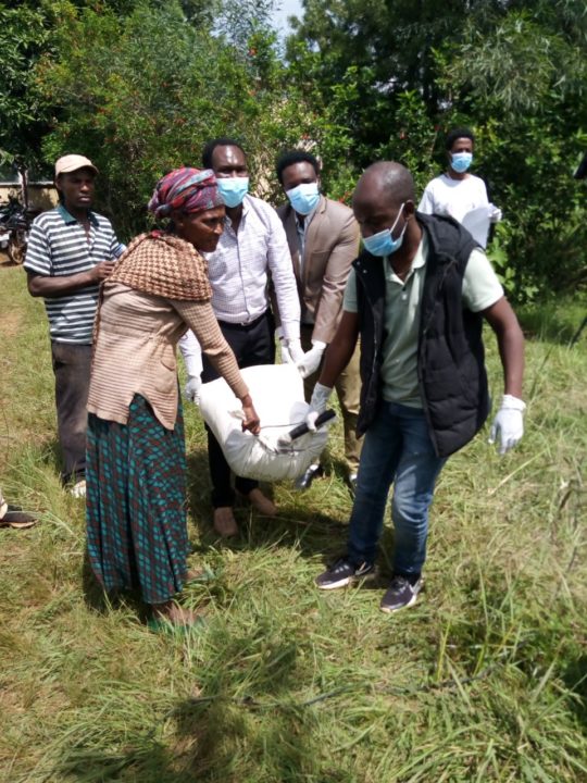 Holt staff help a woman carry a bag of maize/corn home to her family.