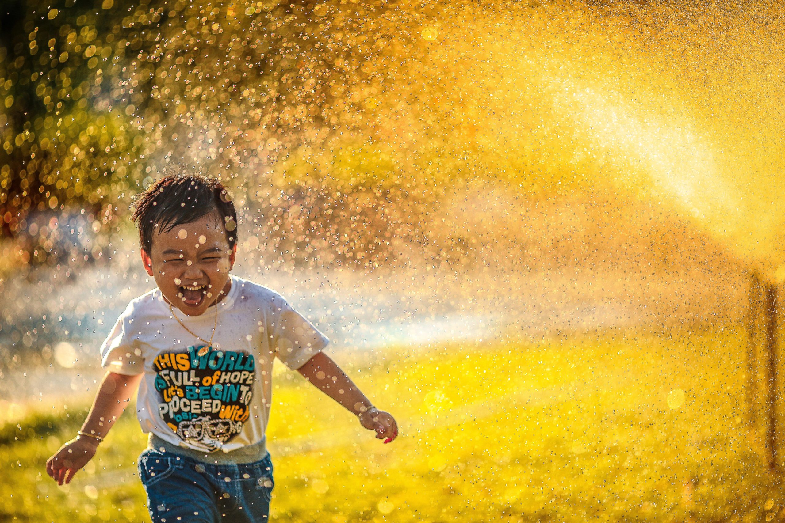 adopted boy with fetal alcohol syndrome running through sprinkler