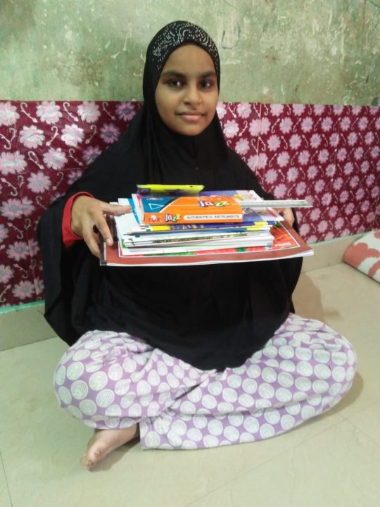 A student holds school supplies provided by her sponsor. 