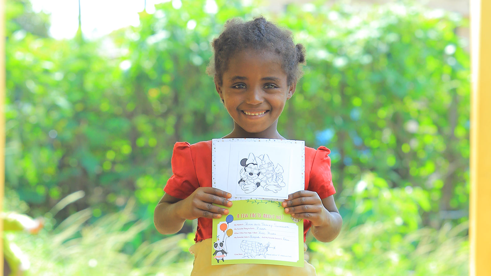 sponsored child smiling with birthday card from sponsor