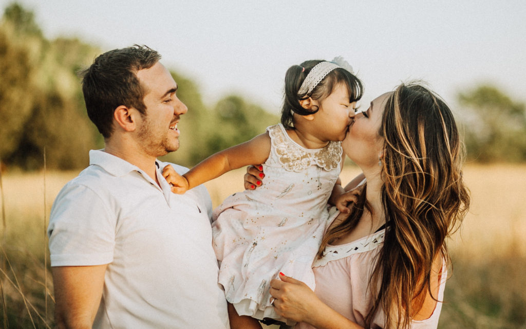 family photo mom kissing daughter dad smiling