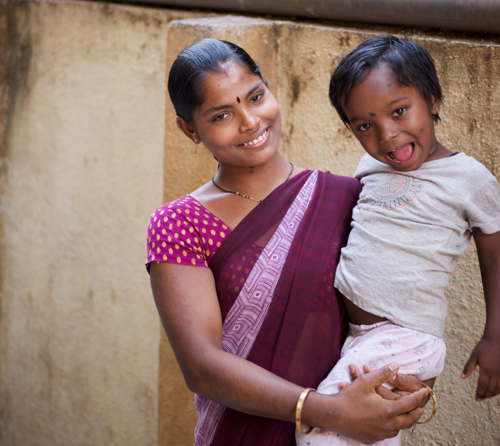 mother holding child and smiling in purple sari