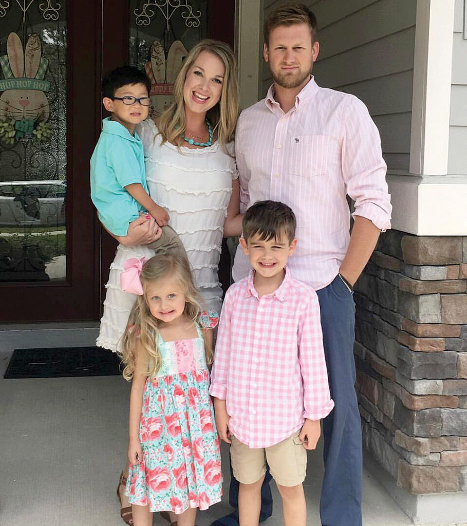 mom dad and three children standing and smiling for a portrait