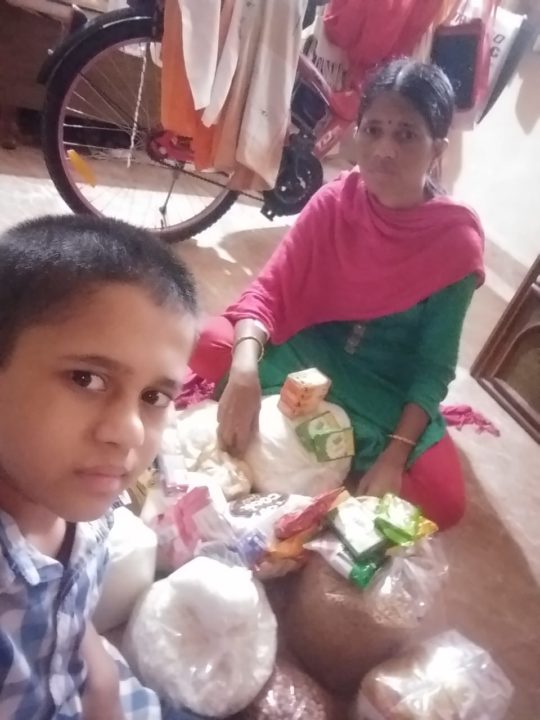 A sponsored boy and his mom sit beside emergency supplies they received to help them get through months of lockdown in India. 