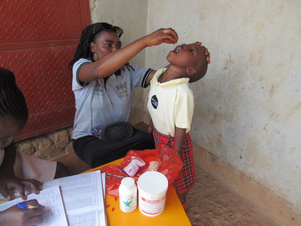 A healthcare worker administers vitamin supplements to a child at a child health camp in rural Uganda.