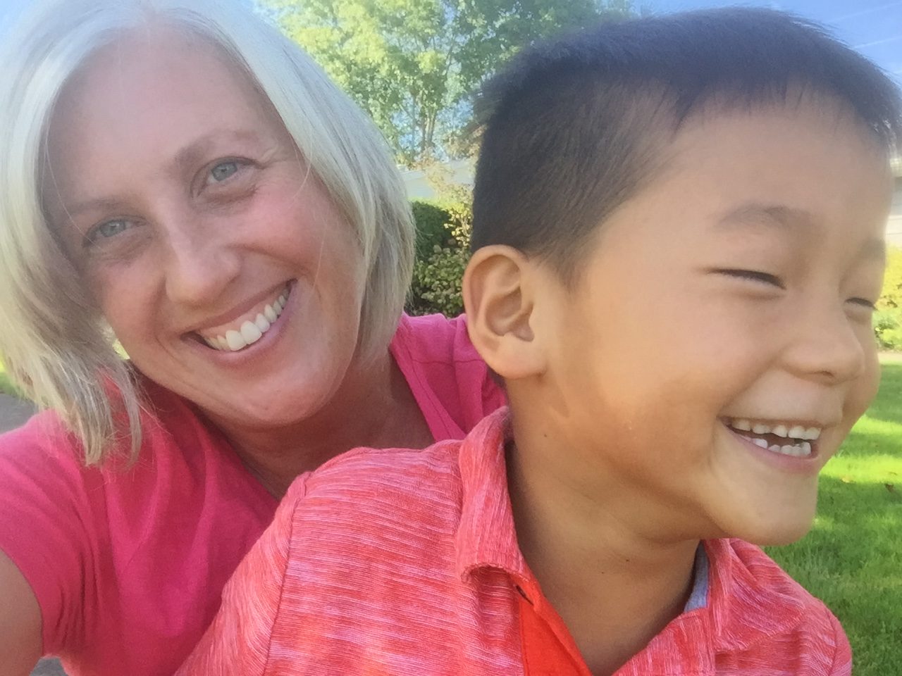 smiling woman looking at camera with adoptive son laughing