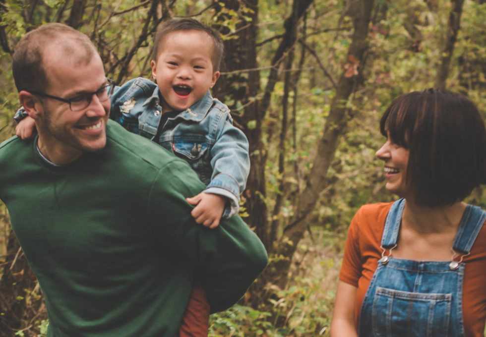 smiling little boy piggybacking on dad with mom walking