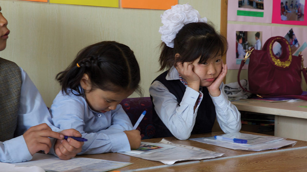 Students listen to a lesson, dressed in the uniforms they received from their sponsors.