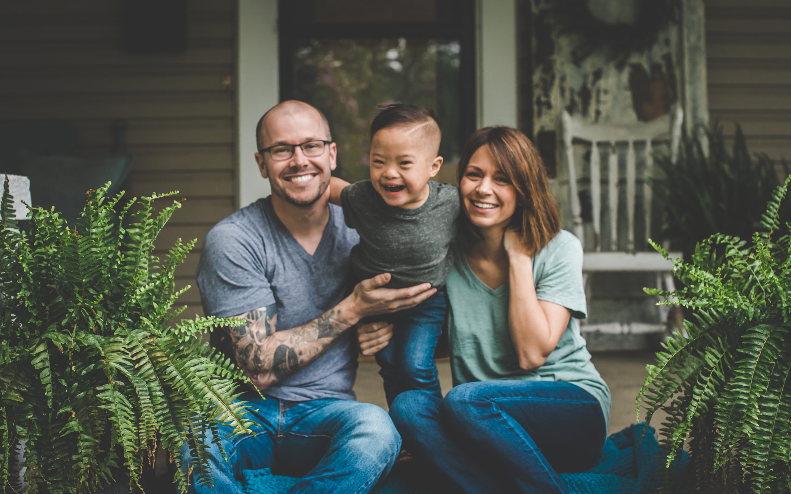 Dad and mom sitting on front porch steps with son adopted from China