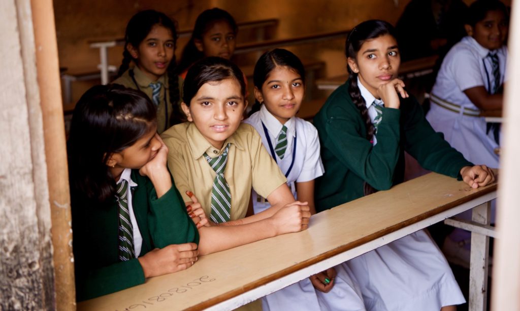 four girls sitting at a desk in school uniforms