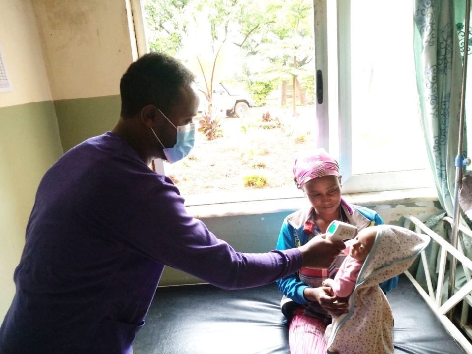A doctor checks the temperature of a child at the mother and child hospital that Holt donors helped build for the people of this community. 
