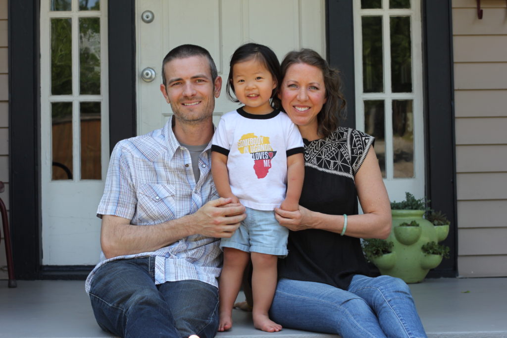 man and woman sitting on porch with toddler standing in between