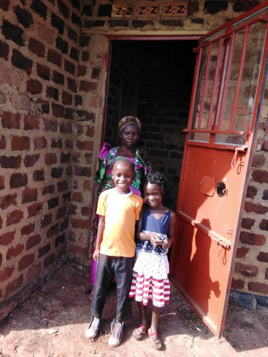 Julius and his family stand in front of their new home that Julius' sponsor helped build for them. 