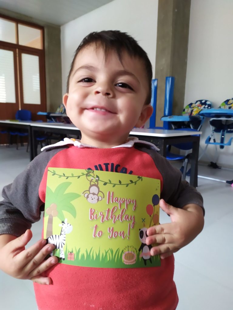 toddler boy smiling holding birthday card