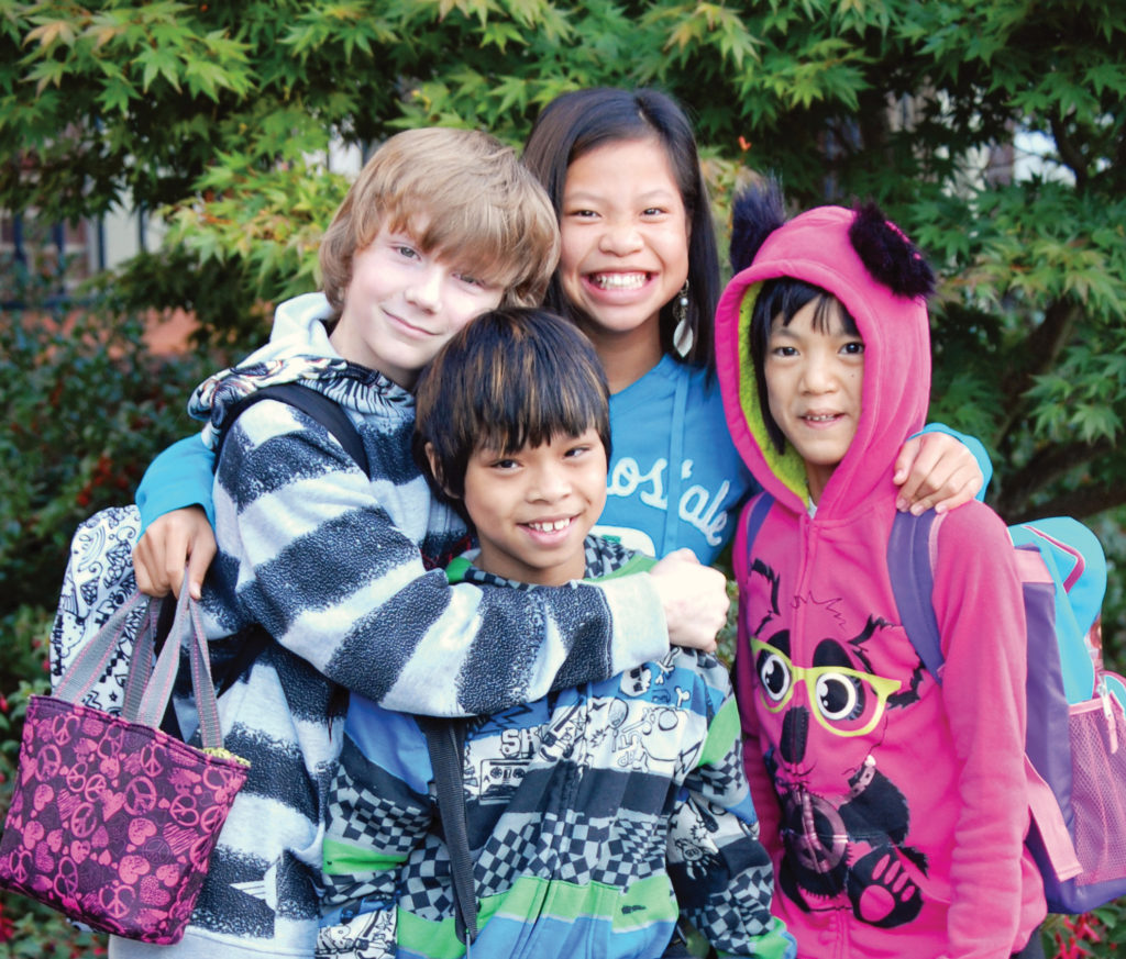 four kids in colorful hoodies smiling