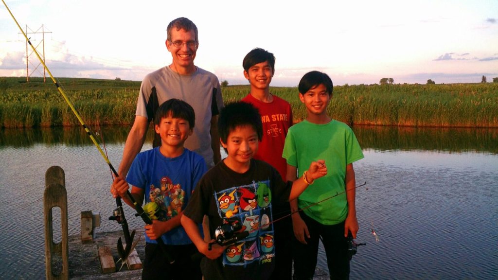 dad and four boys holding fishing poles