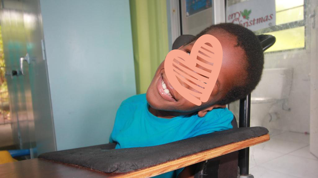 Boy wearing blue shirt smiling in wheelchair