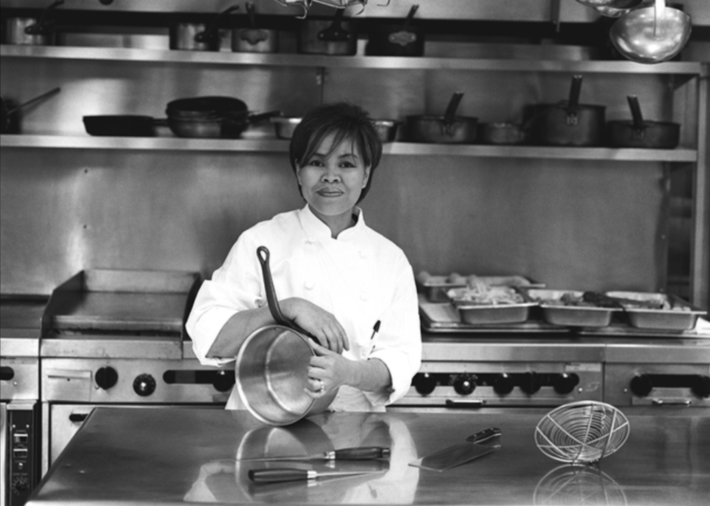 woman in chefs uniform holding a pot