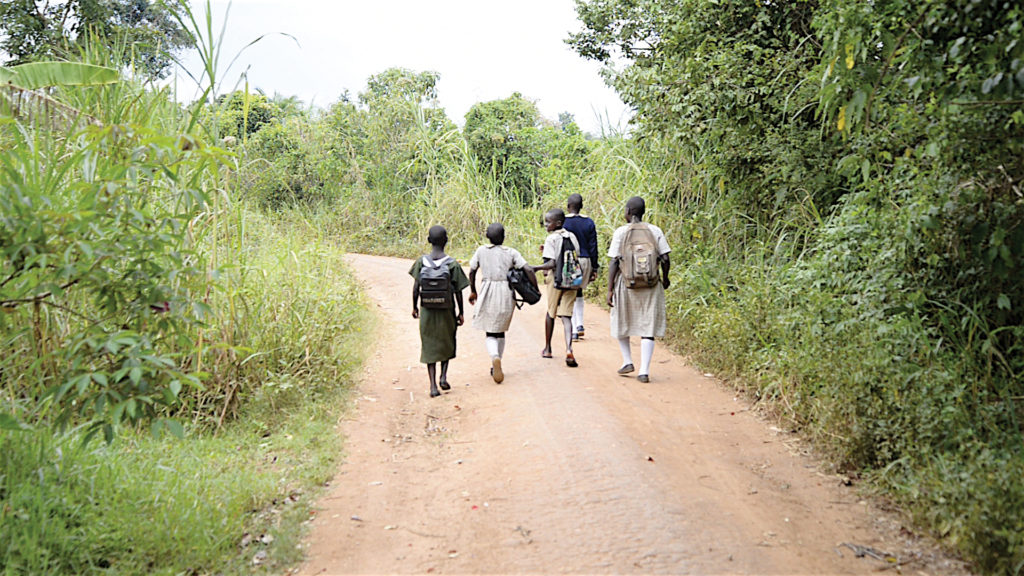 five children walking down a dirt road