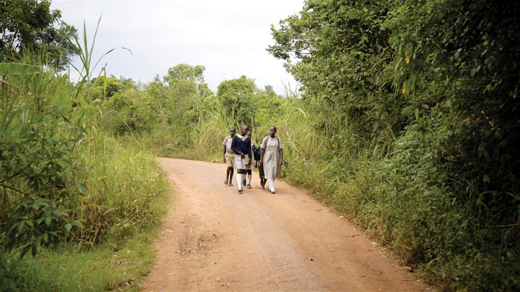 children walking down a dirt road in uganda