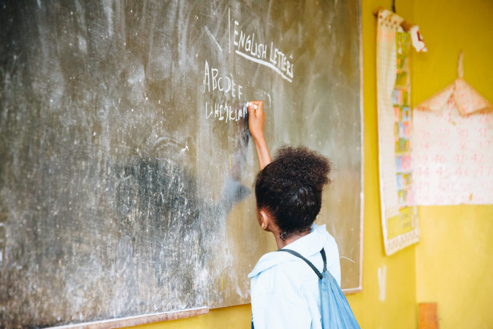 A student writing English letters on the chalkboard at Wallana Kindergarten