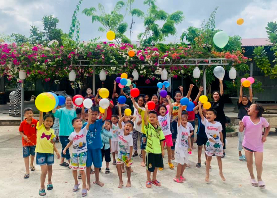 group of kids throwing colorful balloons into the air