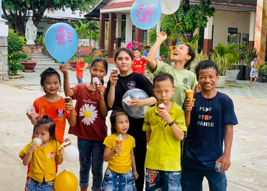 group of children with colorful balloons eating ice cream cones