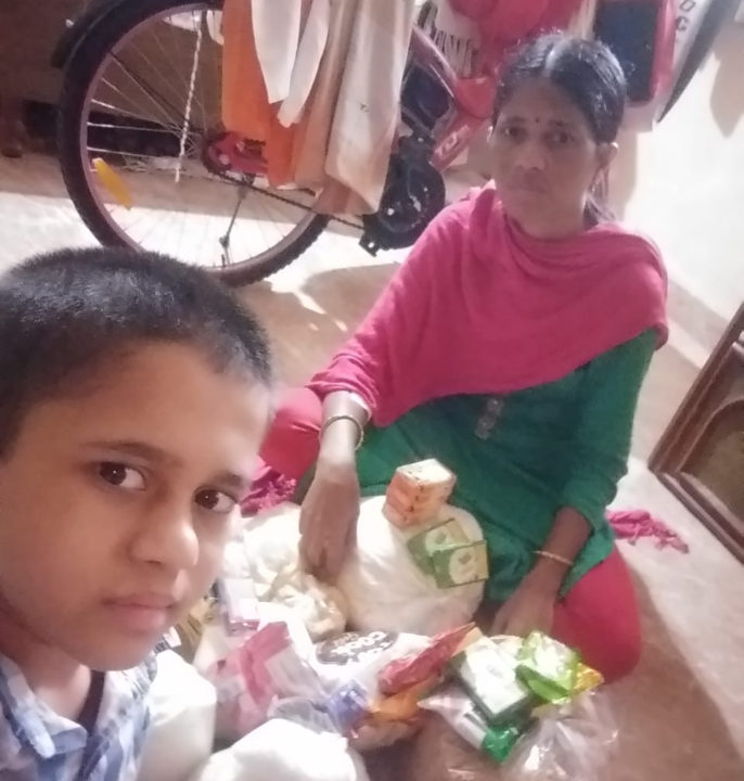 A child in Holt sponsorship and his mom sit beside emergency supplies they received to help them get through months of lockdown due to COVID-19 in India.