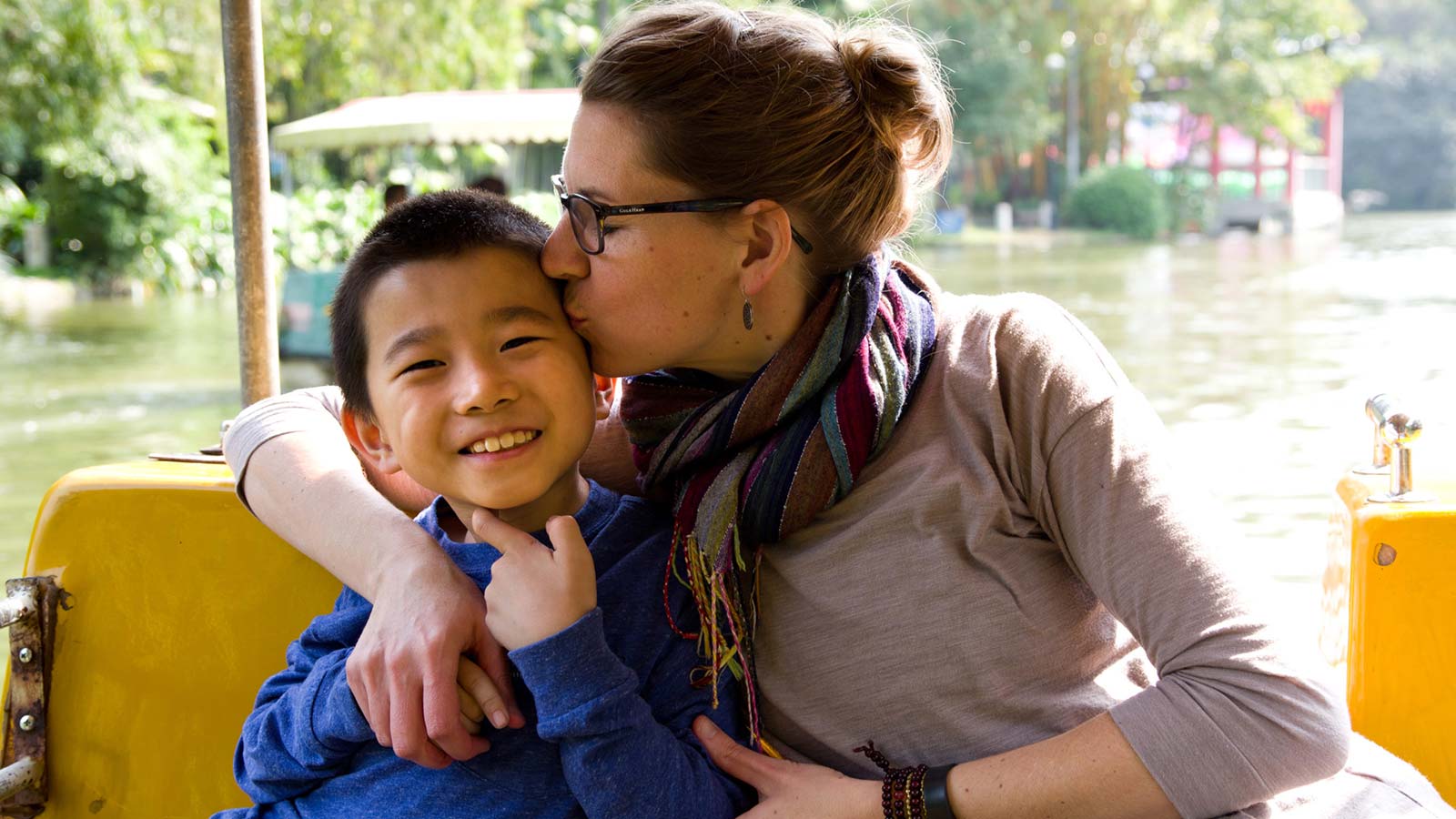 Mom kissing her adoptive son from China on a boat