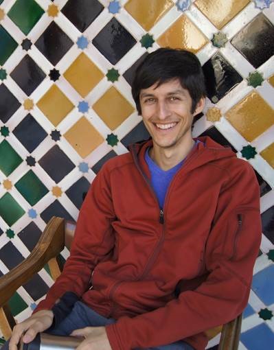 man in red sweater in front of green black and yellow tile wall