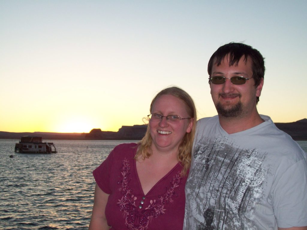 smiling man and woman in front of a sunset reflecting on water
