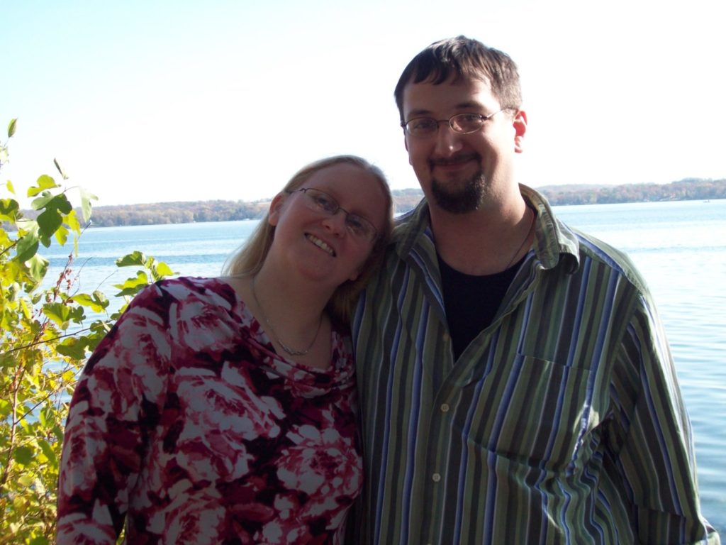 smiling man and woman in front of lake