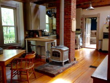 grey wood stove in the middle of a kitchen and dining room