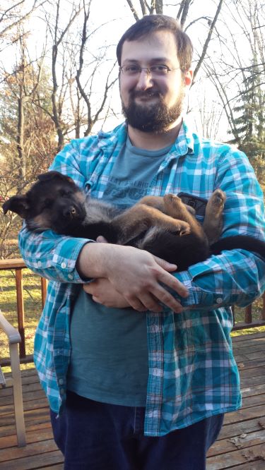 man in blue plaid shirt holding brown puppy