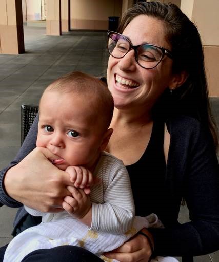 laughing woman holding baby biting womens thumb