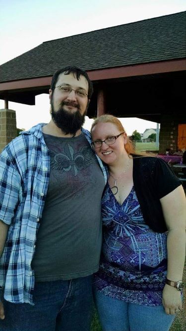 smiling woman with arms around smiling man with beard