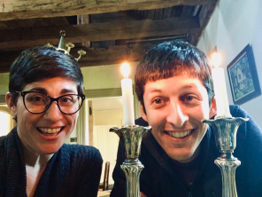 man and woman smiling behind two taper candles