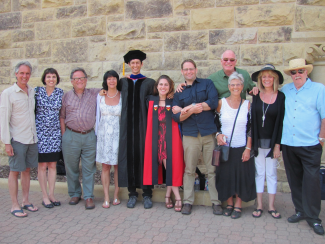 group of people smiling in front of stone wall