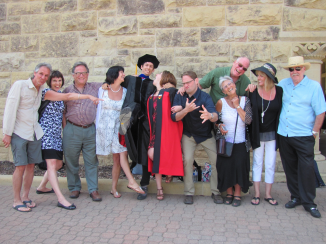 group of people making silly faces in front of stone wall