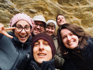 selfie of six smiling people in front of rock formation