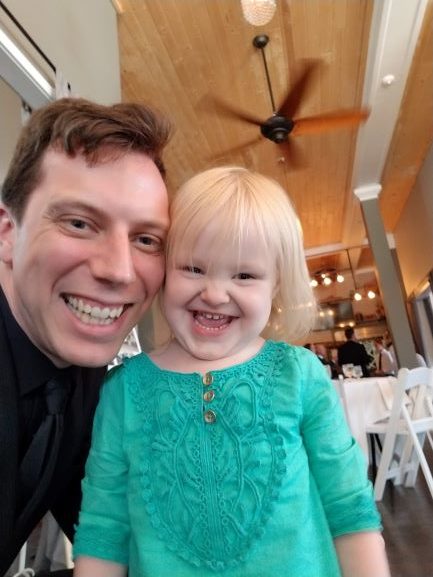 smiling man next to laughing toddler girl