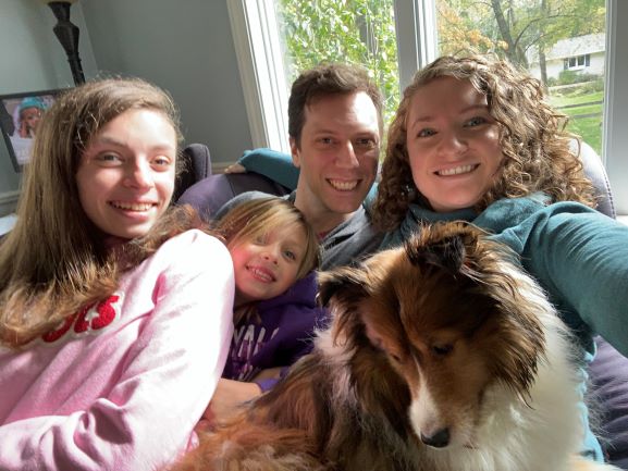 selfie of four people with brown and white dog